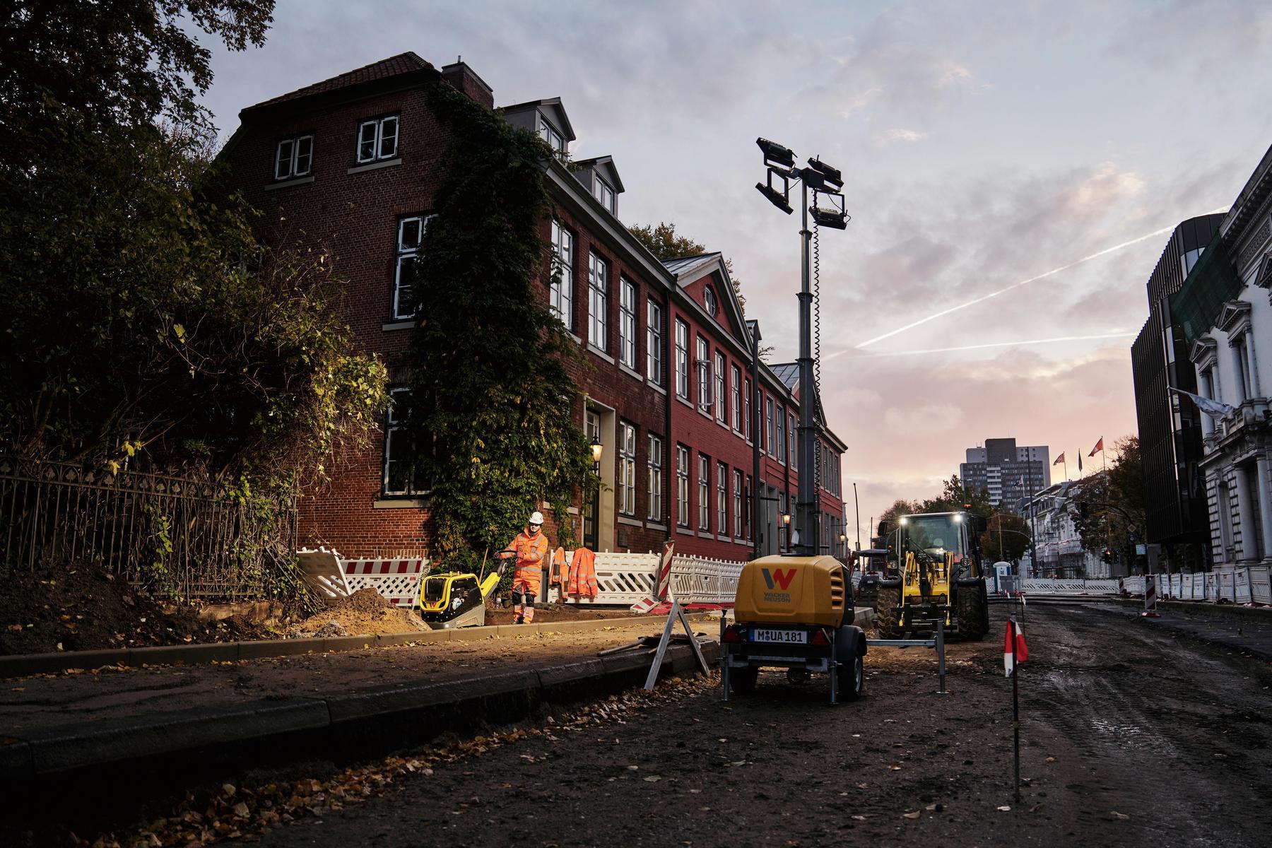 Strabag Baustelle bei Dämmerung mit Wacker Neuson Lichtmast und Baumaschinen im Einsatz